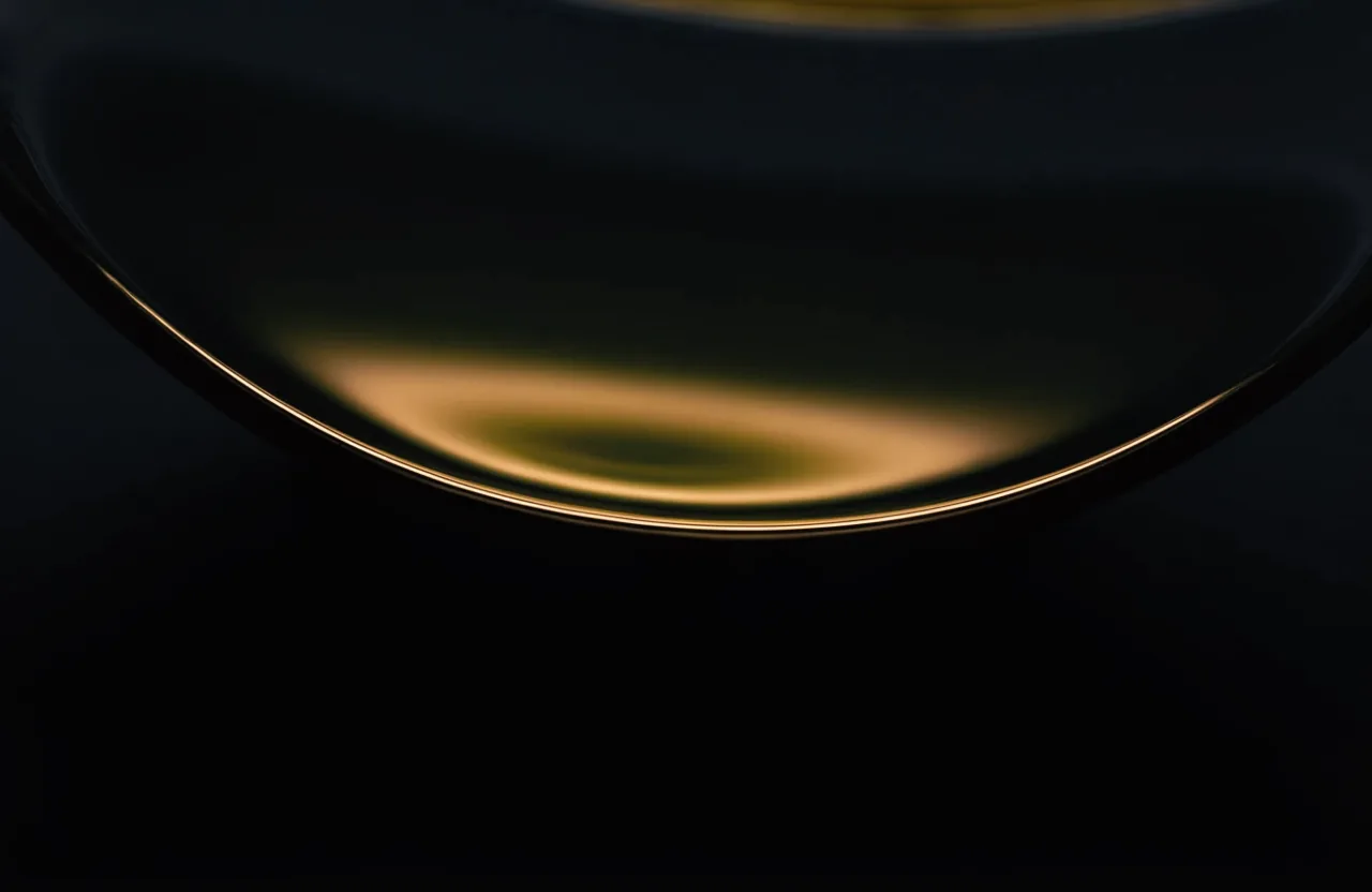 Die Oberfläche von grün-goldenem Olivenöl, ein einzelnes warmes Goldlicht auf dem Rand