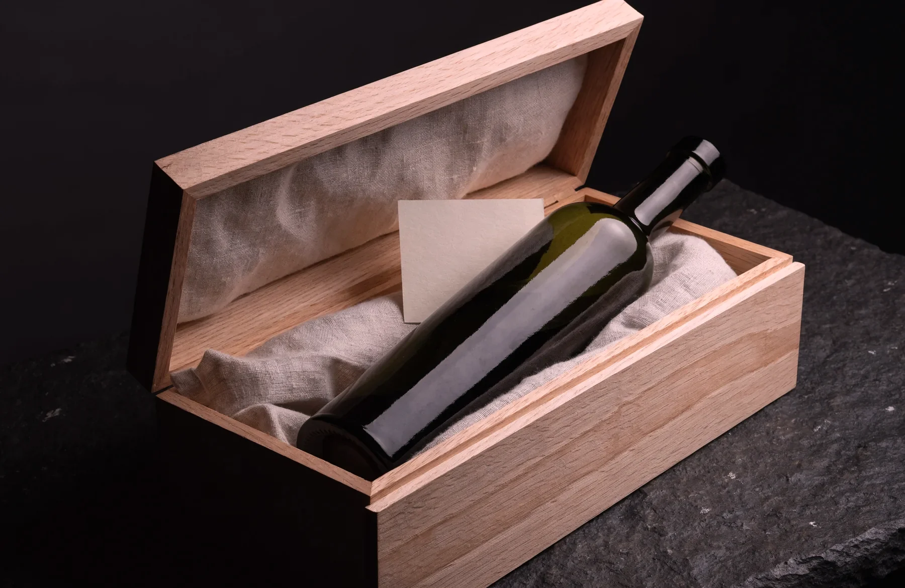 Eine Flasche Farga Milenario in einer offenen Kassette aus heller Eiche mit Leinen und Karte